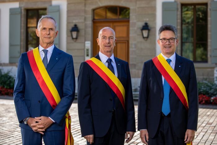Photo du Conseil administratif de Cologny, soit Messieurs Pascal Hornung, Alexandre Bodmer et Edouard Cuendet, portant leur écharpe de magistrat, debout devant l'entrée de la Mairie