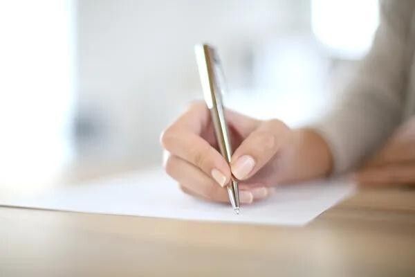 illustration d'une main tenant un stylo au-dessus d'une feuille encore blanche
