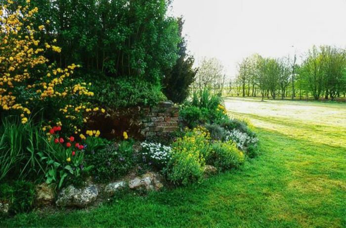 Ein schöner Garten mit einem gepflegten Gemüsegarten, verschiedenen Stauden und einem Arboretum.