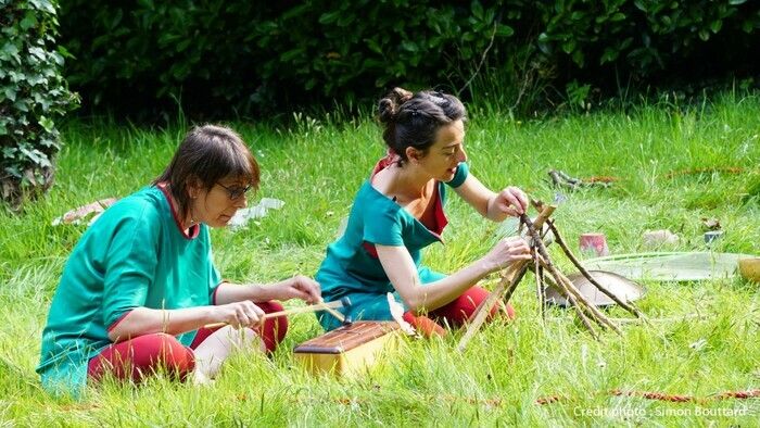 Im Duett spielen eine Schauspielerin und eine Musikerin in einem Garten unter Berücksichtigung der Umgebung: beobachten, fühlen, berühren, hören und erleben, was im Augenblick zum Spielen vorhanden is