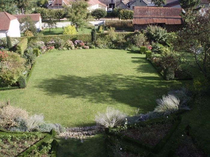 Kommen Sie, einen kleinen Garten lebenskräftiger Pflanzen zu öffnen(entdecken), der von Buchsbäumen strukturiert ist, um eine gemäß den historischen Denkmälern geschützte Kirche.