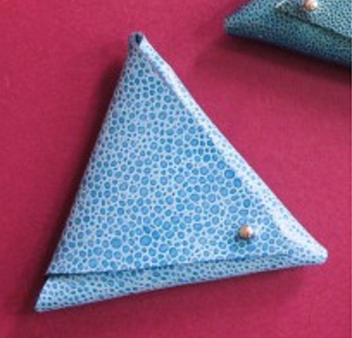 Réalisez un porte-monnaie origami triangulaire à partir de matériaux recyclés : bâches publicitaires, toiles cirées usagées... Trois pliages, deux attaches et le tour est joué. Simple et pratique.